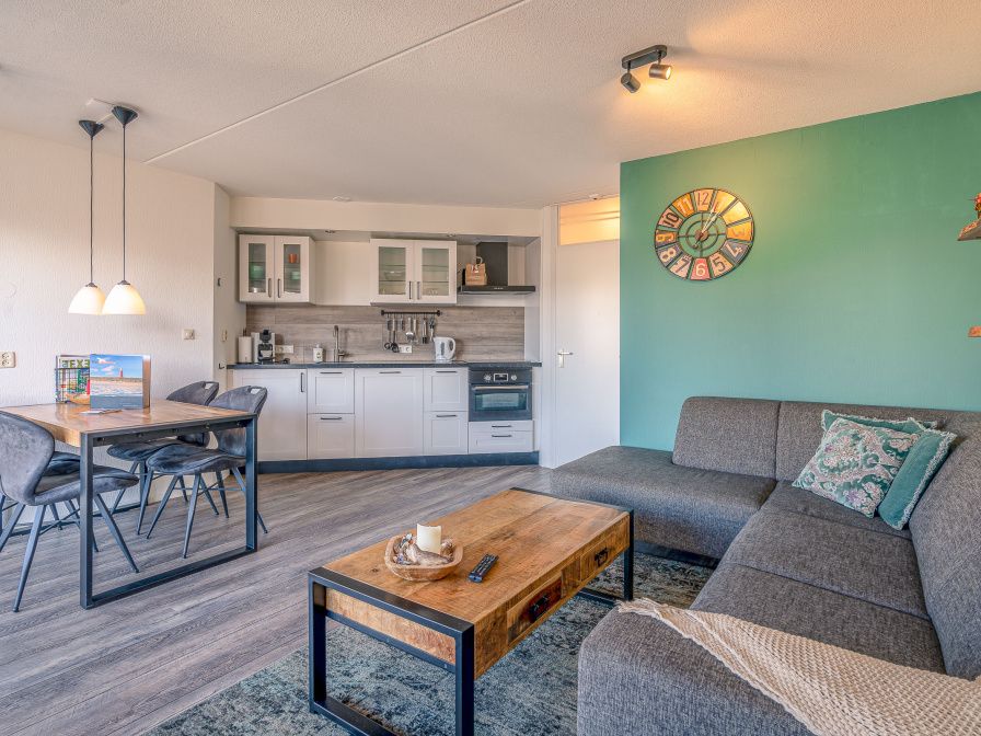 Gemuetliches Wohnzimmer im Appartement Zeedistel 20, De Koog, Texel mit moderner Kueche und bequemer Sitzecke.