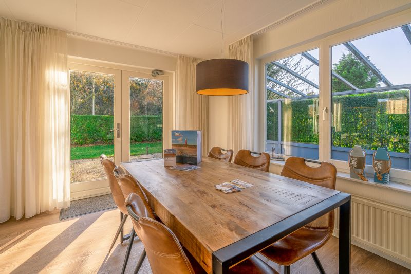 Eethoek in Vakantiehuis Kamperfoelie 89 De Koog Texel met uitzicht op de tuin, ideaal voor maaltijden tijdens je verblijf.