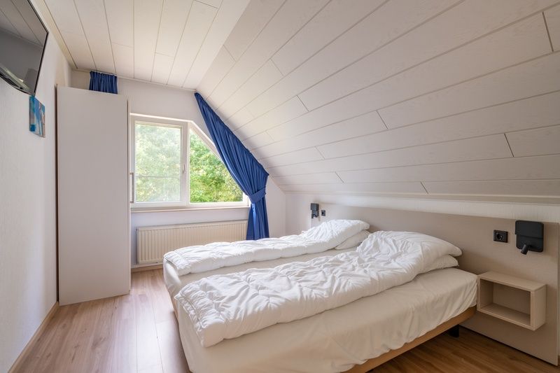 Tweede slaapkamer in Vakantiehuis Kamperfoelie 89 De Koog Texel met comfortabele bedden en uitzicht op de groene omgeving.