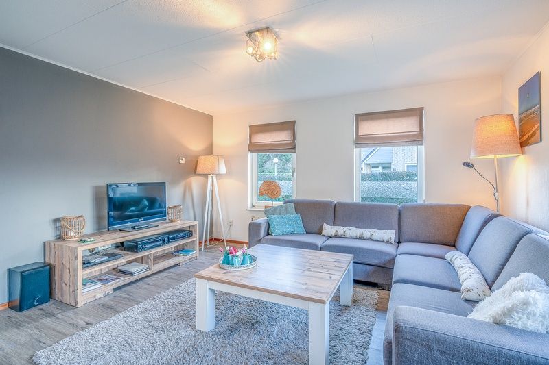 Geraeumiges Wohnzimmer im Ferienhaus Kamperfoelie 87, De Koog, Texel mit stilvoller Einrichtung und Fernseher.