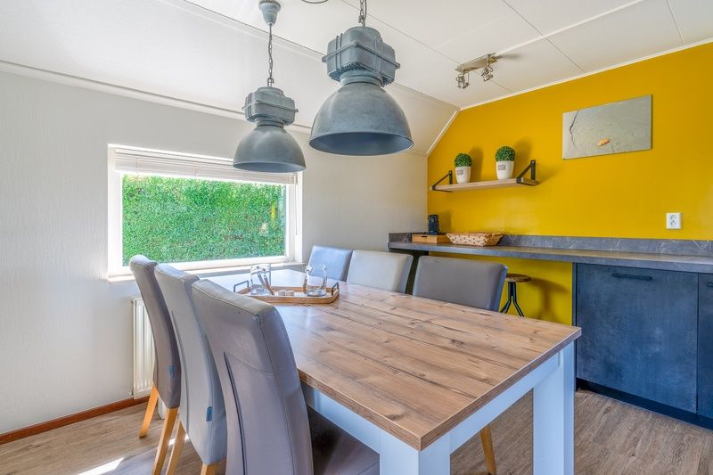 Eetruimte in Vakantiehuis Kamperfoelie 71, De Koog, Texel, met houten tafel en moderne verlichting.