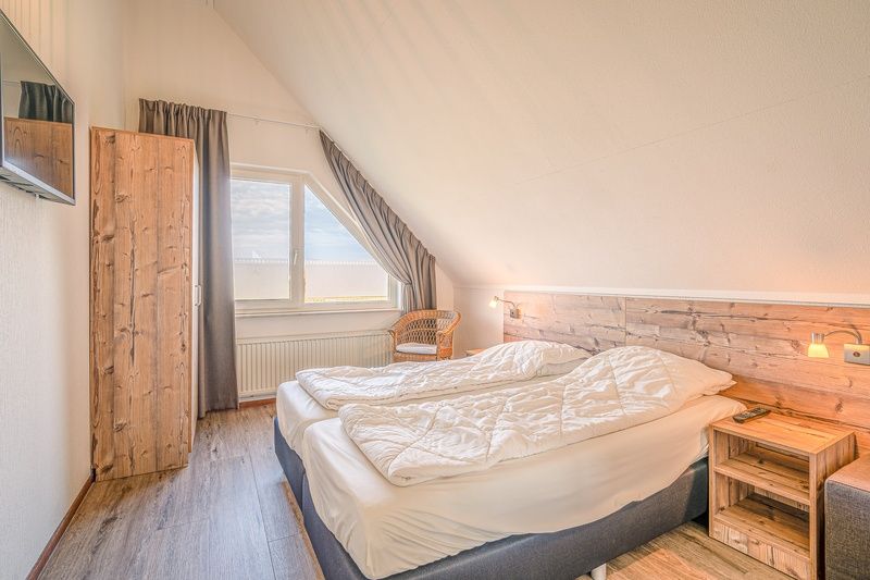 Slaapkamer in Vakantiehuis Kamperfoelie 71, De Koog, Texel, met comfortabel bed en houten details.