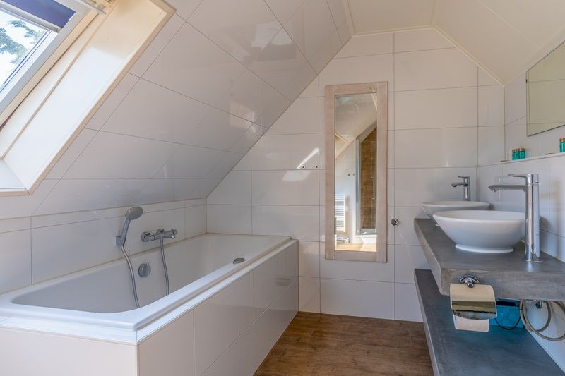 Luxe badkamer in Vakantiehuis Kamperfoelie 71, De Koog, Texel, met ligbad en dubbele wastafel.