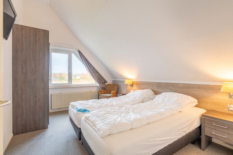 Helles Schlafzimmer im Ferienhaus Honeysuckle 59, De Koog, Texel mit Blick auf die gruene Umgebung.