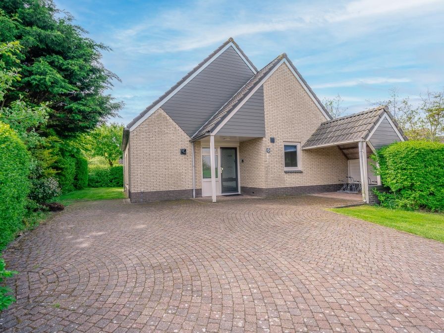 Vooraanzicht van Vakantiehuis Kamperfoelie 65 in De Koog, Texel met ruime oprit en groene omgeving.