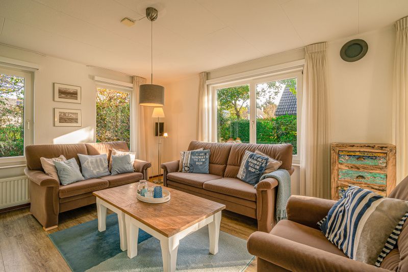 Gezellige woonkamer van Vakantiehuis Kamperfoelie 65, De Koog, Texel met comfortabele banken en veel lichtinval.