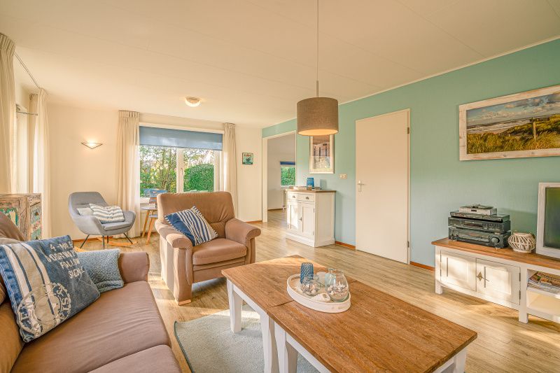 Ruime woonkamer in Vakantiehuis Kamperfoelie 65, De Koog, Texel met houten vloer en stijlvolle decoratie.