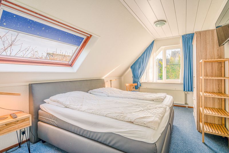 Slaapkamer in Vakantiehuis Kamperfoelie 65, De Koog, Texel met comfortabel bed en dakraam.