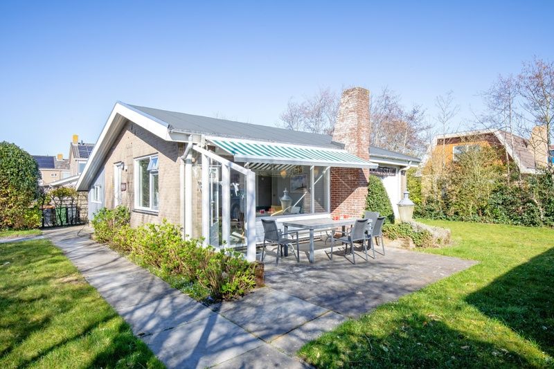 Terras met zonnescherm bij De Schutstal vakantiehuis in De Koog, Texel