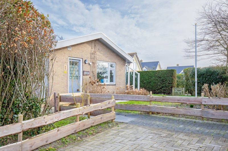 Voorgevel van De Schutstal vakantiehuis met houten hek in De Koog, Texel
