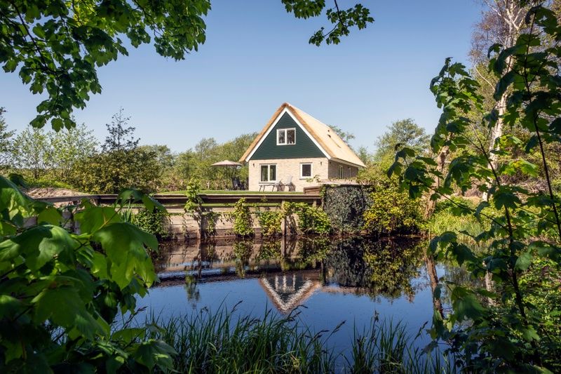 Landhuis De Wije Blick, Ferienhaus in De Koog Texel, das sich in einem ruhigen Teich spiegelt.