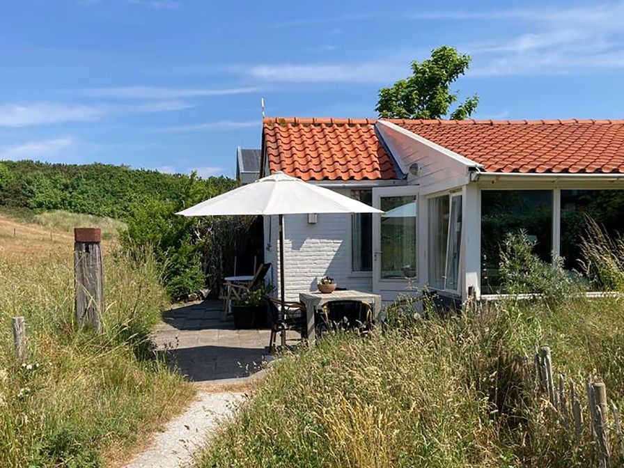 Ferienhaus Achter de Brem in De Koog, Texel mit sonniger Terrasse und gruener Umgebung.