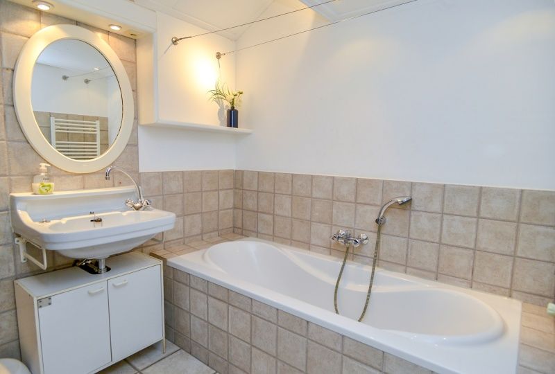 Geraeumiges Badezimmer mit Badewanne im Ferienhaus Achter de Brem, De Koog, Texel fuer hoechsten Komfort.