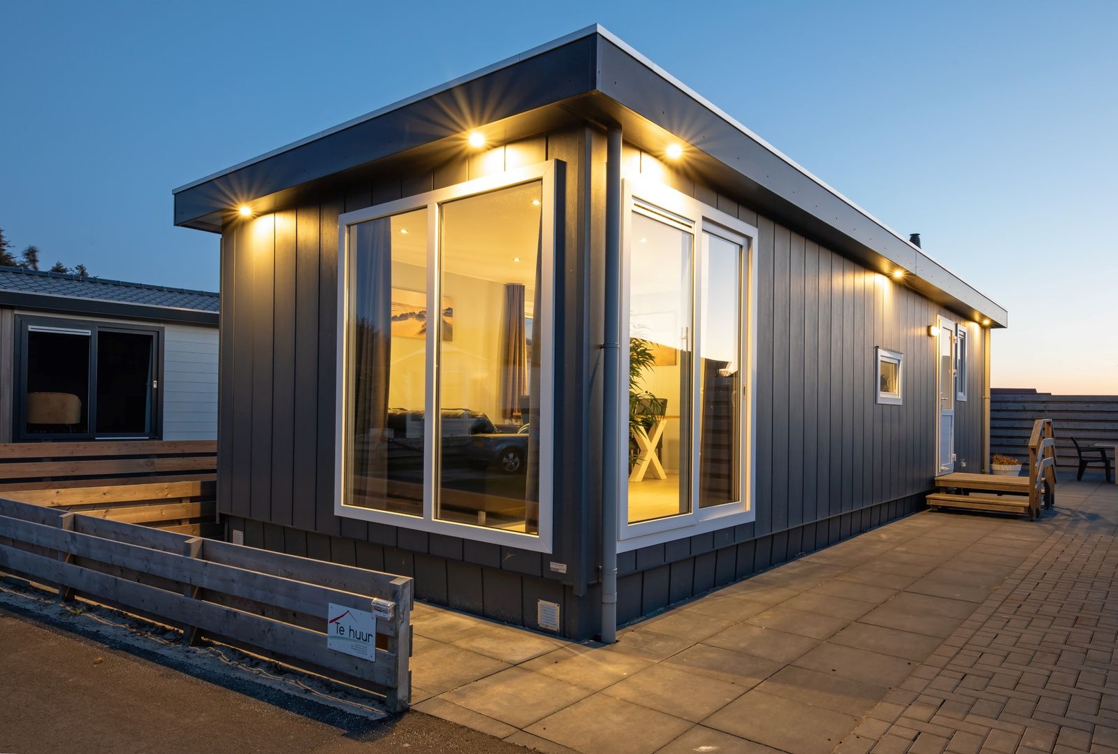 Buitenkant van Chalet Bregkoog 261 bij Chaletpark Bregkoog, De Koog, Texel, sfeervol verlicht in de avond.