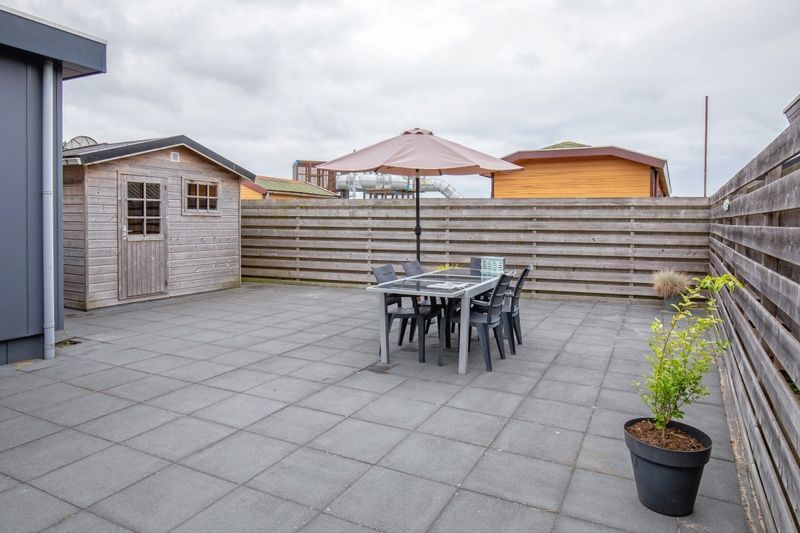 Zonnig terras met parasol bij Chalet Bregkoog 261, Chaletpark Bregkoog, De Koog, Texel, perfect voor een gezellige barbecue.