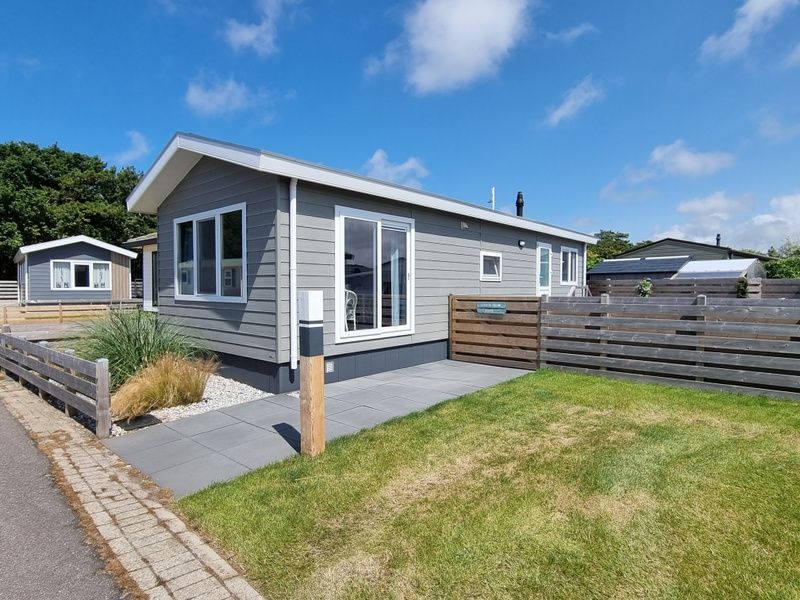 Exterieur van Chalet Bregkoog 82 in De Koog, Texel met zonnig terras en moderne uitstraling.
