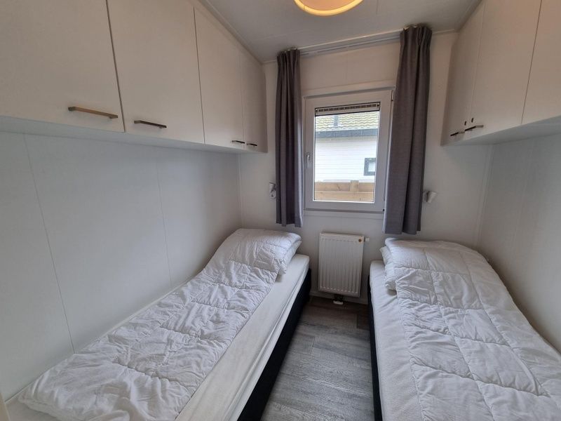 Tweede slaapkamer in Chalet Bregkoog 82, De Koog, Texel met twee eenpersoonsbedden en praktische opbergruimte.