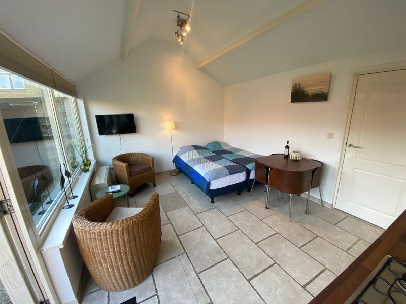 Binnenruimte van Studio Ooster - Brink 28 in De Koog, Texel, met zithoek en slaapgedeelte.