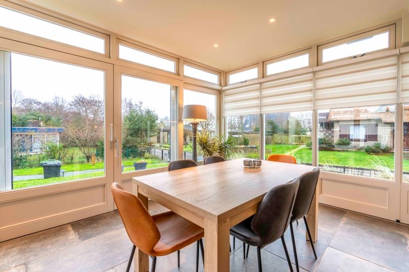 Eetkamer in Huis ter Duin, vakantiehuis in De Koog, Texel met uitzicht op groene omgeving.