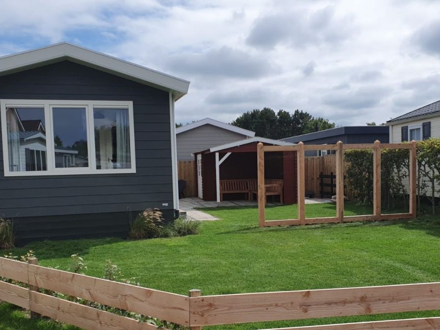 Chalet Bregkoog 154 in De Koog op Texel met groene tuin en houten hekwerk.