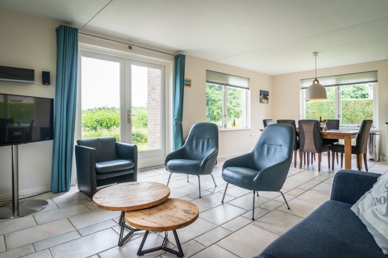 Ruime woonkamer in Villa 6 personen, De Koog Texel, met comfortabele zitplaatsen en uitzicht op de tuin.