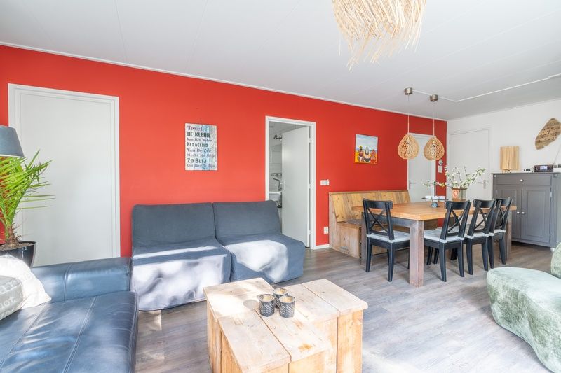 Ess- und Sitzecke im Bungalow De Nagtegaal 21, Bungalowpark De Nagtegaal, De Koog, Texel mit warmen roten Akzenten.