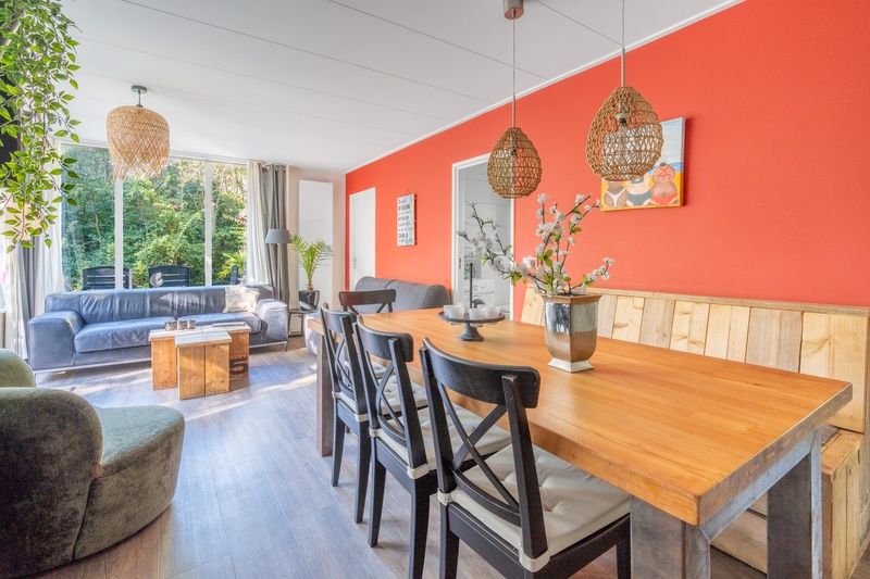 Geraeumiges Esszimmer im Bungalow De Nagtegaal 21, Bungalowpark De Nagtegaal, De Koog, Texel mit Holztisch und modernen Stuehlen.