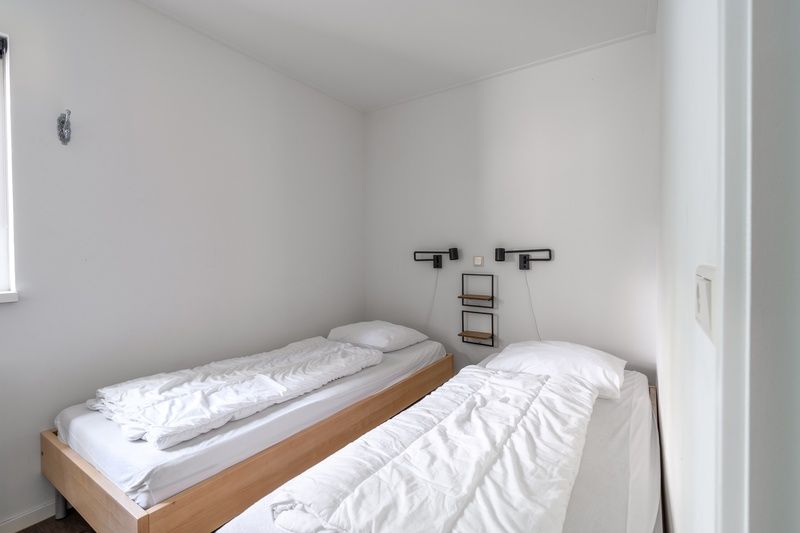 Komfortables Schlafzimmer im Bungalow De Nagtegaal 21, Bungalowpark De Nagtegaal, De Koog, Texel mit zwei Einzelbetten.