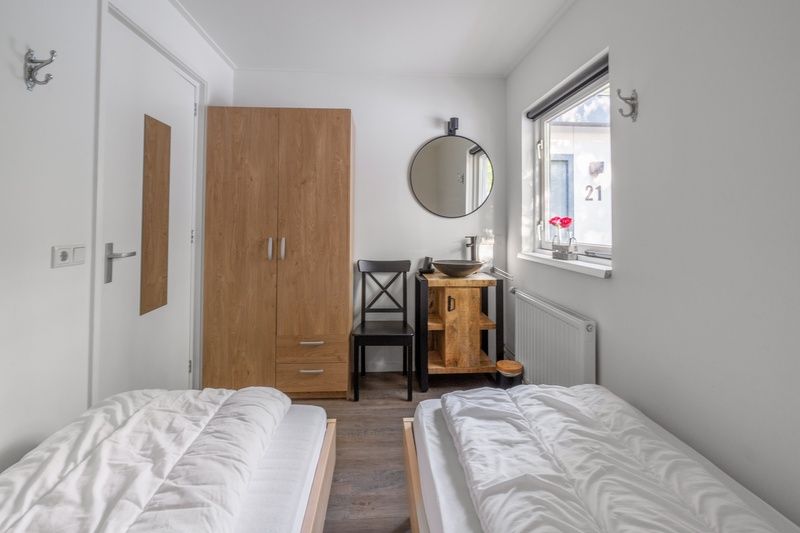 Schlafzimmer mit rustikalen Details im Bungalow De Nagtegaal 21, Bungalowpark De Nagtegaal, De Koog, Texel mit Holzmoebeln.