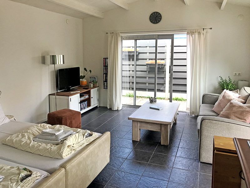 Gezellige woonkamer van Zomerhuisje Schoo in De Koog, Texel, met uitzicht op de tuin.