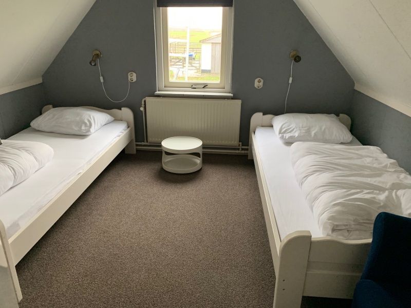 Sfeervolle slaapkamer met twee bedden in Vakantiehuis 0386 De Koog Texel, ideaal voor kinderen op de Waddeneilanden.