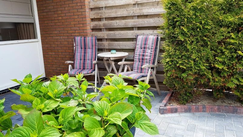 Sonnige Terrasse im Ferienhaus 2, De Koog, Texel mit bequemen Stuehlen fuer einen entspannten Nachmittag.