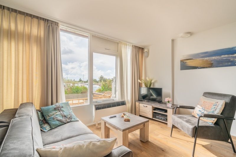 Lichte leefruimte van Appartement Juliana 076 Eilandzicht in De Koog, Texel met comfortabele zithoek en buitenzicht.