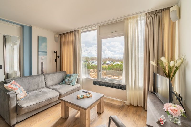 Stijlvolle binnenruimte van Appartement Juliana 076 Eilandzicht, De Koog, Texel met uitzicht op groene omgeving.