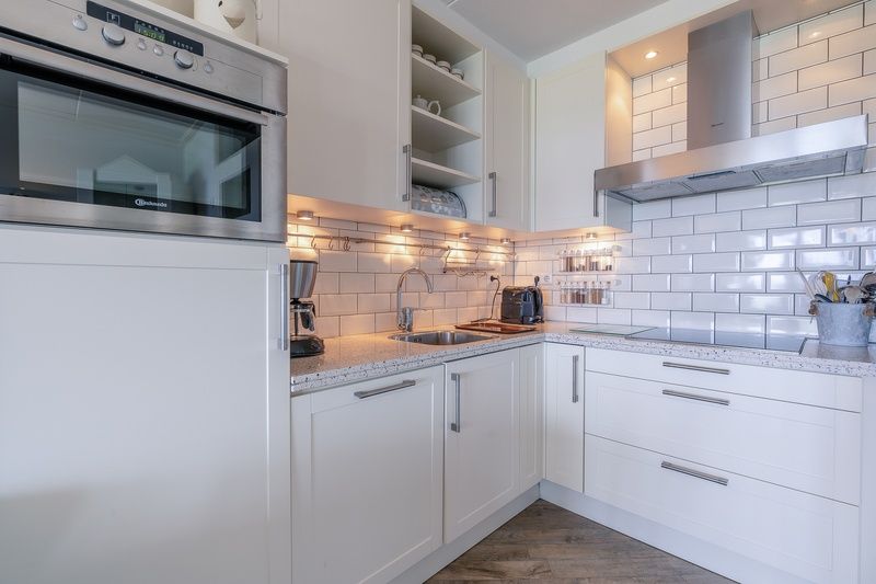 Moderne keuken van Appartement Juliana 106 Zeezicht in De Koog, Texel met witte kasten en luxe apparatuur.