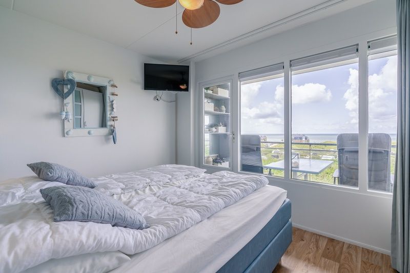 Slaapkamer van Appartement Juliana 106 Zeezicht in De Koog, Texel met comfortabel bed en uitzicht op zee.