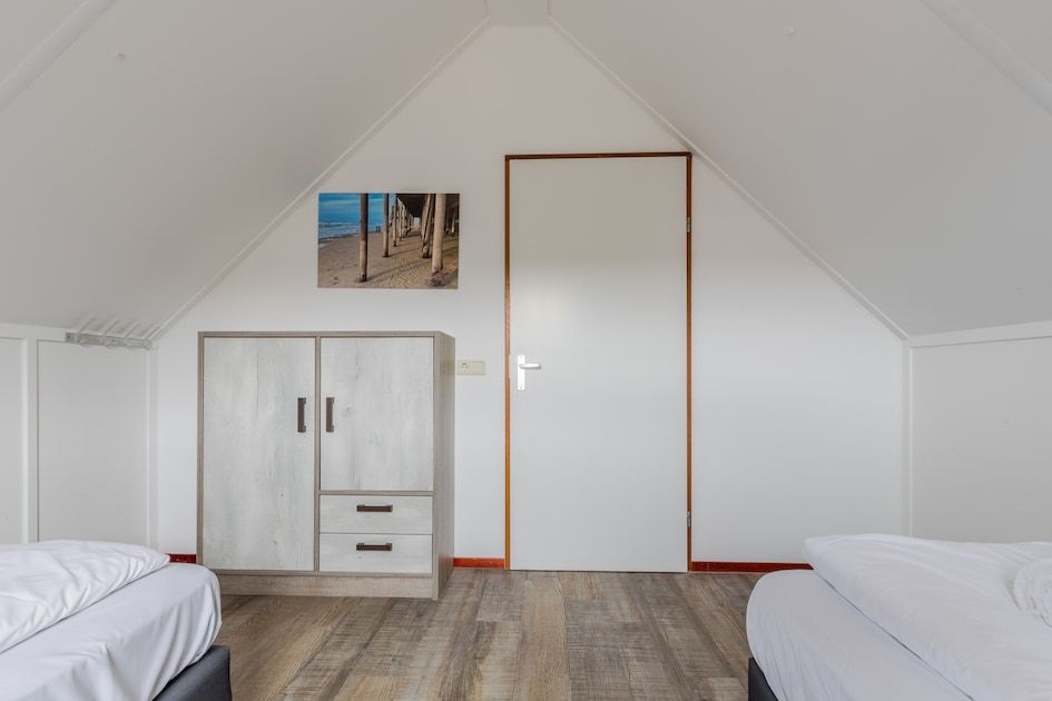Schlafzimmer im Bungalow T6B Comfort in De Koog, Texel, mit Holzboden und heller Einrichtung, ideal fuer einen erholsamen Aufenthalt auf den Watteninseln.