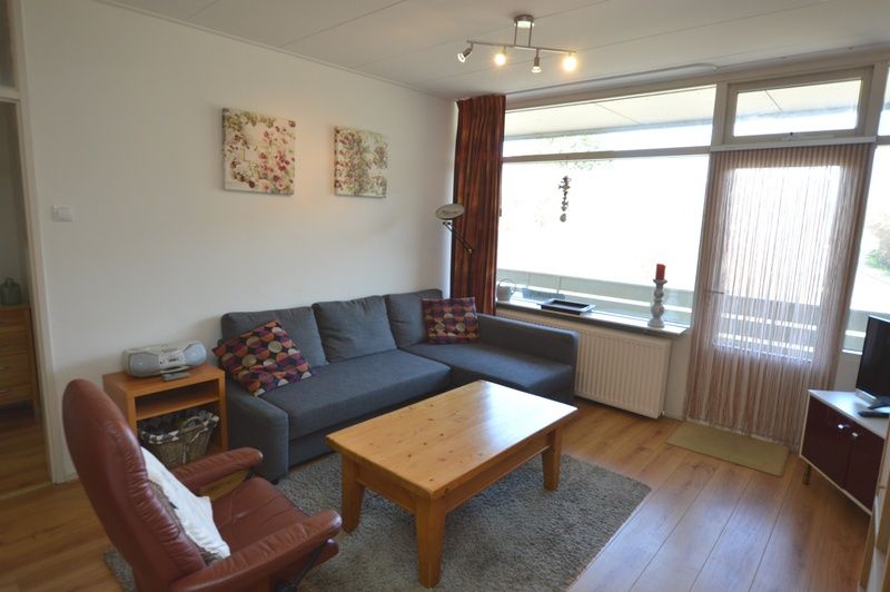 Lichte woonkamer in Appartement Kerckeland 50, De Koog, Texel met ruime bank en decoratieve elementen.