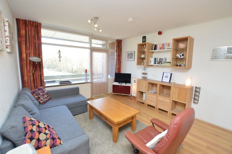 Moderne woonkamer van Appartement Kerckeland 50, De Koog, Texel met uitnodigende zithoek en boekenplanken.