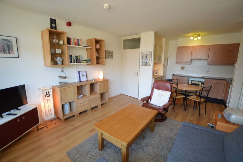 Ruime leefruimte in Appartement Kerckeland 50, De Koog, Texel met toegang tot de keuken en comfortabele stoelen.