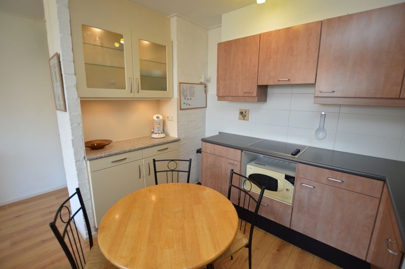 Stijlvolle keuken in Appartement Kerckeland 50, De Koog, Texel met houten kastjes en ronde eettafel.