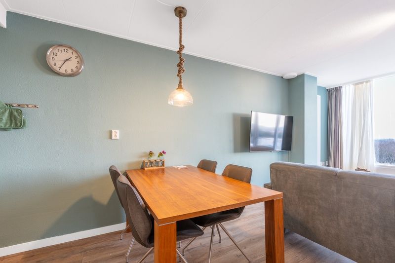 Essecke im Appartement Juliana 124 Eilandzicht, De Koog, Texel mit Holztisch und modernen Stuehlen.