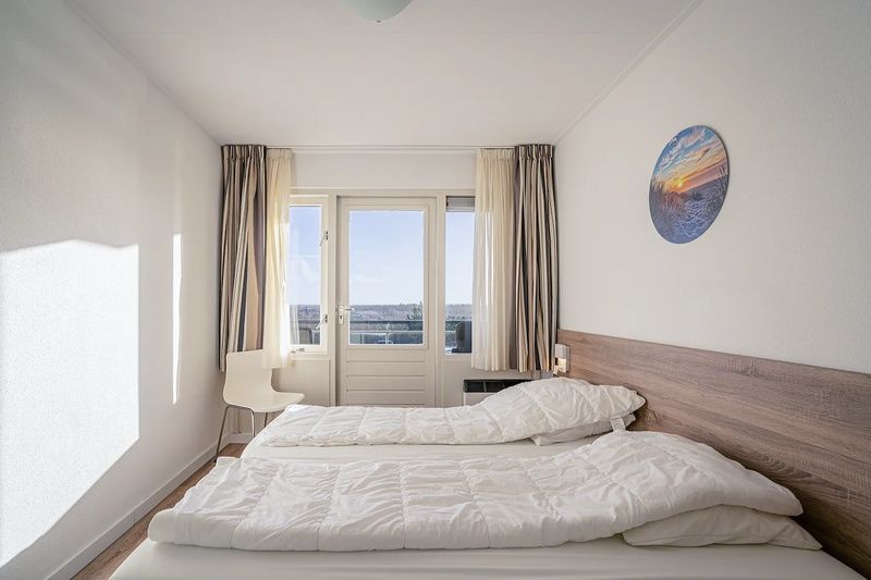 Geraeumiges Schlafzimmer im Apartment Juliana 124 Eilandzicht, De Koog, Texel mit Zugang zum Balkon.