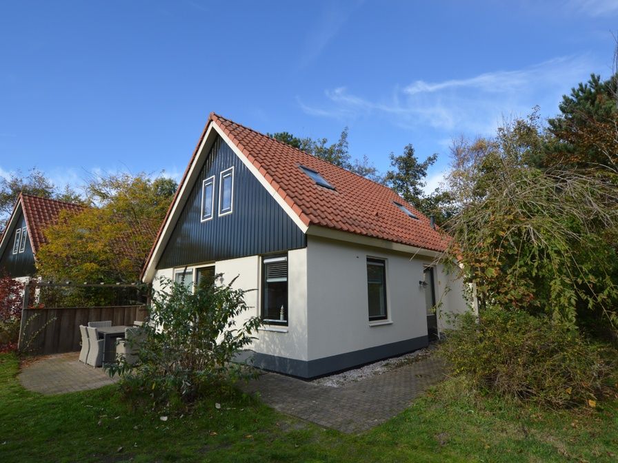 Das Ferienhaus 7G in De Koog, Texel, hat ein schoenes Aeusseres mit einem roten Dach und einer gruenen Umgebung.