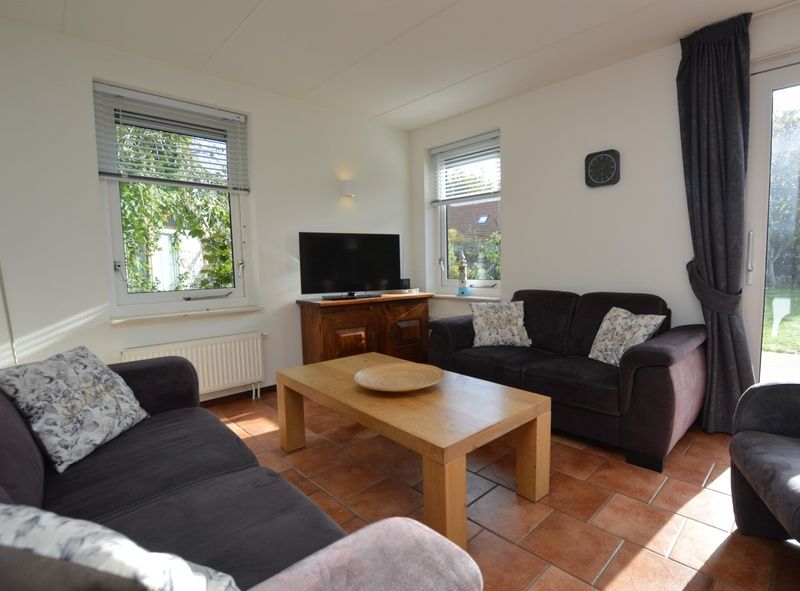 Gemuetliches Wohnzimmer des Ferienhauses 7G in De Koog, Texel mit bequemen Sofas und viel Tageslicht.