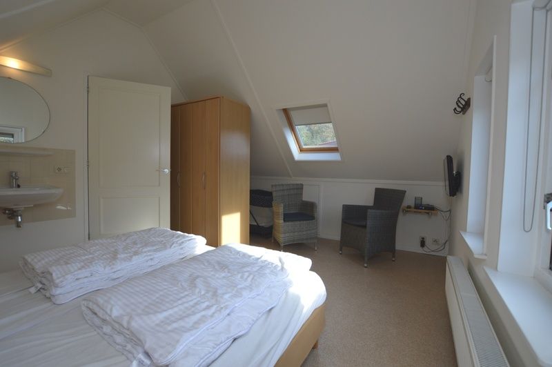 Mansardenzimmer im Ferienhaus 7G, De Koog, Texel mit Dachfenster und gemuetlicher Sitzecke.