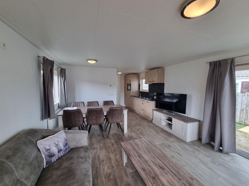 Modern furnished living room of Chaletpark Bregkoog - Chalet 240 De Texelse Berg, De Koog, Texel with open kitchen.