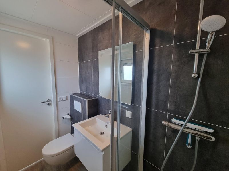 Modern bathroom in Chaletpark Bregkoog - Chalet 240 De Texelse Berg, De Koog, Texel with shower and sink.