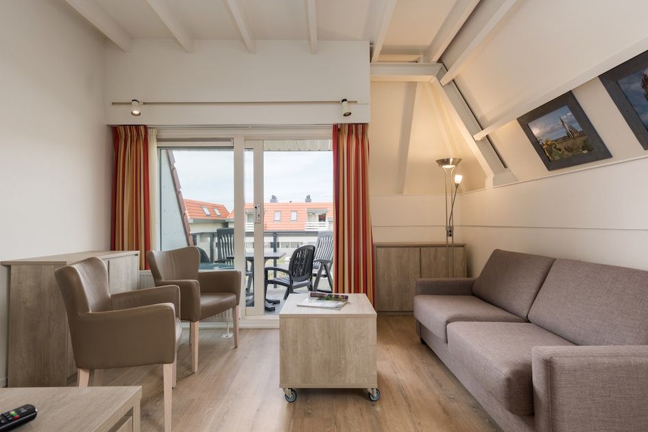 Gezellige woonkamer van C Appartement Comfort 4 in De Koog, Texel, met uitzicht op het terras en moderne inrichting.