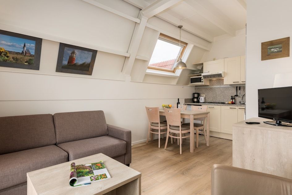 Gezellige woonkamer van C Appartement Comfort 4 in De Koog, Texel, met moderne keuken en eetruimte, ideaal voor een ontspannen verblijf.